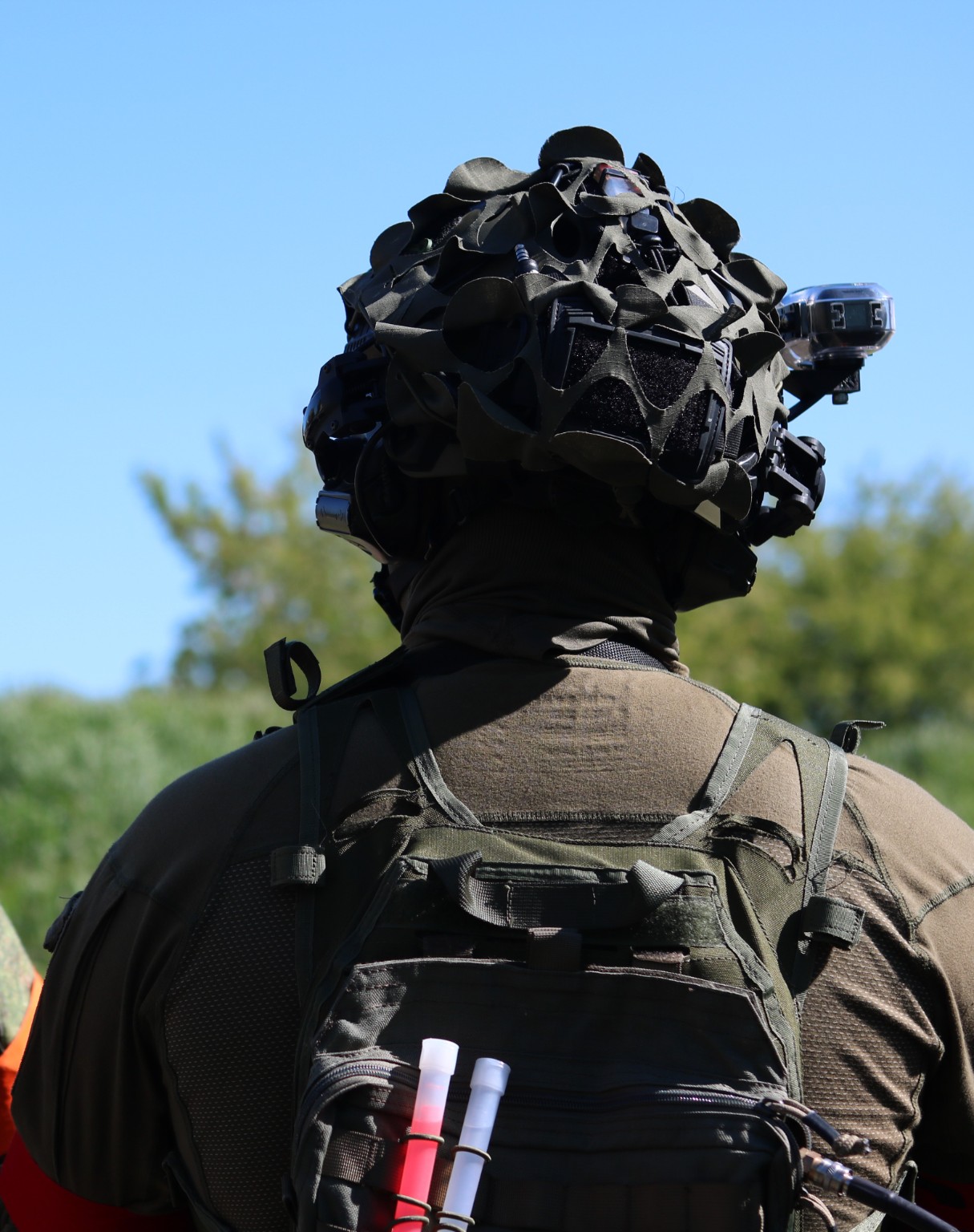 Airsoft-Spieler mit Helm und Kamera von hinten